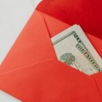A red envelope containing U.S. dollar bills, symbolizing wealth and gifting.